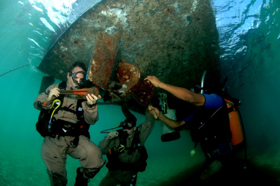 US Navy 080724-N-3093M-019 Senior Chief Diver Billy Gilbert, assigned to Mobile Diving and Salvage Unit (MDSU) 2, uses a pipe wrench to remove a damaged propeller on a small patrol boat