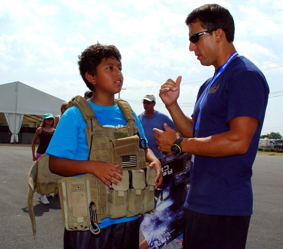 US Navy 080722-N-2888Q-007 Explosive Ordnance Technician Bobby Wood, right, talks with a young boy wearing an EOD 9 bomb disposal suit during Healthy Kids Day at the Delaware State Fair