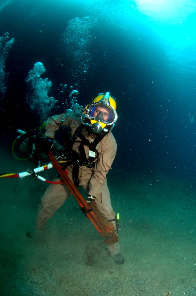 US Navy 080726-N-3093M-007 Chief Warrant Officer Guy Inzunza carries a pipe wrench across the seabed during a dive from the Military Sealift Command rescue and salvage ship USNS Grasp (ARS 51)