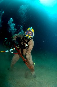 US Navy 080726-N-3093M-007 Chief Warrant Officer Guy Inzunza carries a pipe wrench across the seabed during a dive from the Military Sealift Command rescue and salvage ship USNS Grasp (ARS 51)