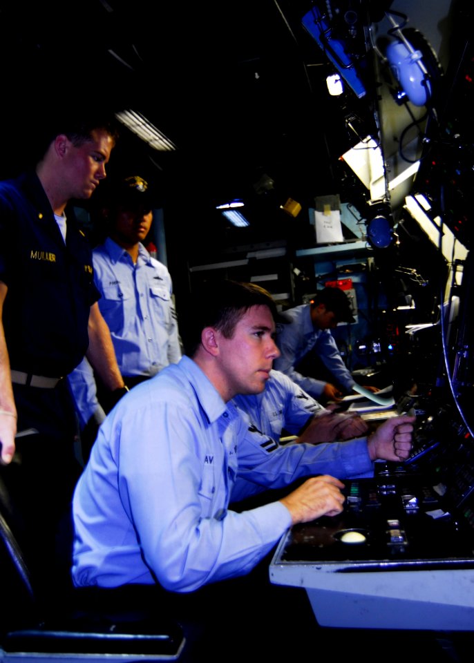 US Navy 080729-N-9520G-029 Ensign Kyle Muller, fire control officer looks on as Fire Controlman 2nd Class Ryan Pavelich receives reports during a mock naval surface fire support training exercise
