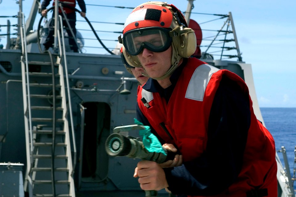 US Navy 080723-N-9123L-001 Hull Technician Fireman Branden Schmidt of Riverside, Calif., advances a hose during a flight deck firefighting evolution aboard the guided-missile destroyer USS John S. McCain (DDG 56)