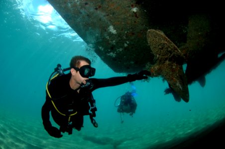 US Navy 080724-N-3093M-001 Construction Mechanic 2nd Class Aaron Heldreth, assigned to Underwater Construction Team (UCT) 2, inspects a patrol boat's propeller with a member of the Saint Kitts Coast Guard photo