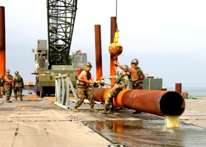 US Navy 080731-N-1424C-336 Seabees assigned to Amphibious Construction Battalion (ACB) 1 and Amphibious Construction Battalion (ACB) 2 unhook crane cables from the pile