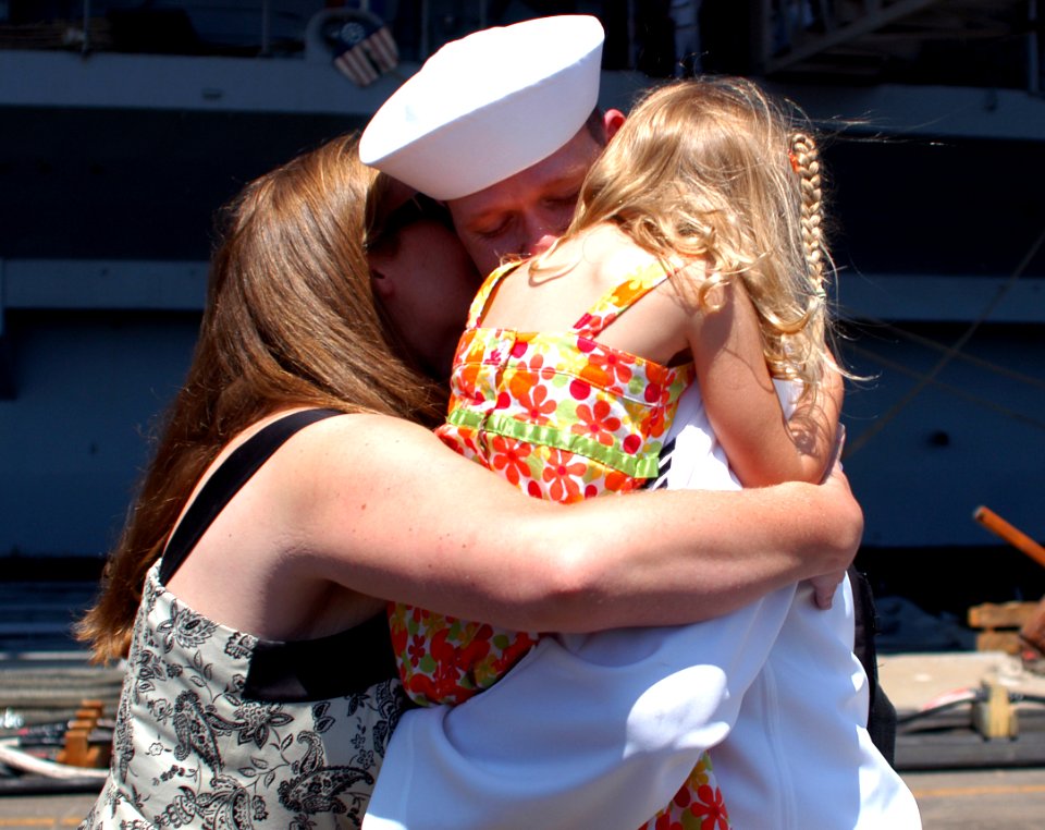 US Navy 080807-N-7029R-065 Aerographer's Mate 1st Class Jeffrey Jackson embraces his wife and daughter after departing the aircraft carrier USS Kitty Hawk (CV 63) at Naval Air Station North Island
