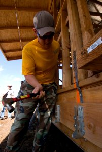 US Navy 080809-N-6674H-007 Chief Intelligence Specialist (Sel.) John Reeder, assigned to Joint Intelligence Operations Command, hammers supports for a deck to be built on a new house for a Habitat for Humanity community service