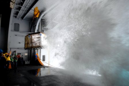 US Navy 080808-N-4005H-047 A wall of sea water crashes into the hangar bay of the Nimitz-class aircraft carrier USS Ronald Reagan (CVN 76), while Sailors assigned to the deck department guide pallets of supplies aboard during a photo
