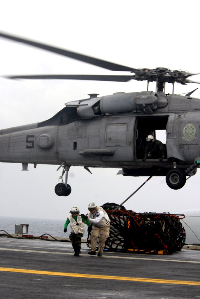 US Navy 080808-N-7730P-079 Storekeeper 1st class Shanty Casimiro and an unidentified midshipman sprint across the flight deck of the aircraft carrier USS Ronald Reagan (CVN 76) to clear the rotor wash after attaching a sling to