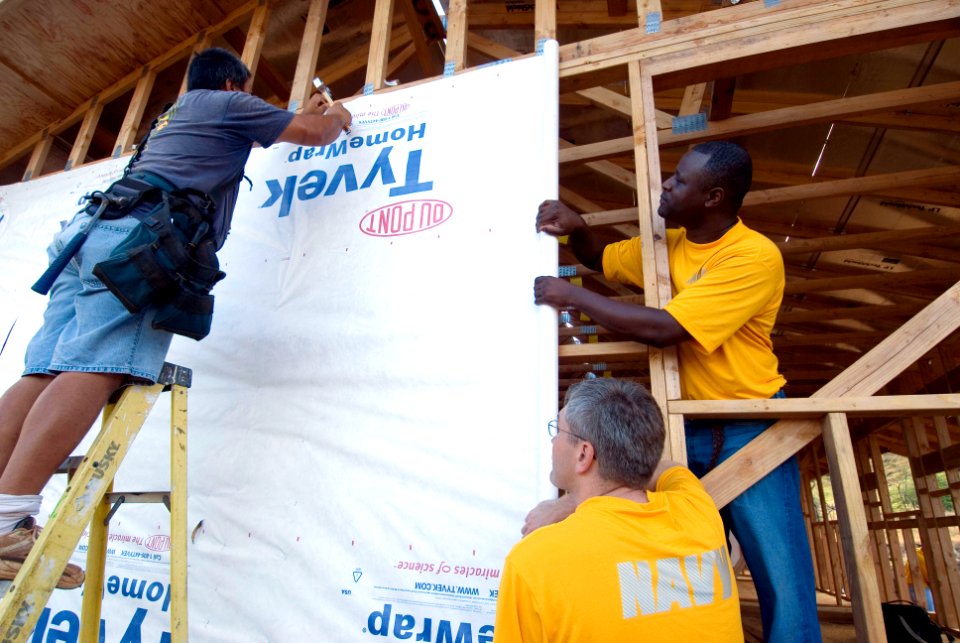 US Navy 080809-N-6674H-002 Navy Region Hawaii chief petty officer selectees help homeowner Aelii Solomom, left, staple insulation wrap during the construction of his home during a Habitat for Humanity community service project