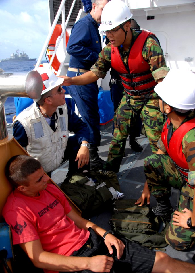 US Navy 080805-N-9758L-109 Hospital Corpsman 3rd Class Michael Mullin and Korean sailors discuss possible treatments for Coast Guard Fireman Logan Schindlerduring