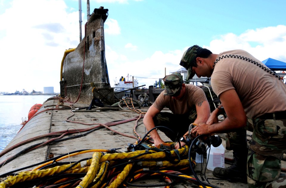US Navy 080809-N-8933S-162 Navy Diver 1st Class James Ohalek and Boatswain's Mate 1st Class William Bailey clean dive helmets after a dive under the former Soviet submarine-turned museum, Juliett 484, in Providence