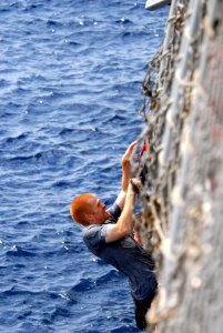 US Navy 080815-N-1635S-004 Electronics Technician 3rd Class Colby Karaim, from Montana, climbs back up to the flight deck of the Arleigh Burke-class guided-missile destroyer USS Howard (DDG 83) during a scheduled swim call