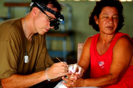 US Navy 080813-N-4515N-445 Lt. Cmdr. Nathan Uebelhoer, a medical augmentee embarked aboard the amphibious assault ship USS Kearsarge (LHD 3), removes a growth from a Nicaraguan women's thumb