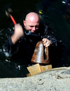 US Navy 080813-N-8933S-101 Navy Diver 1st Class Brent Robinson hammers wedges into a split in the hull where a dongle ripped through the former Soviet submarine-turned-museum Juliett 484