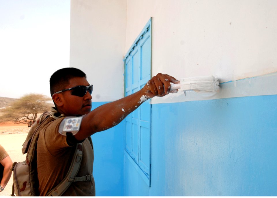 US Navy 080816-N-3560G-092 Builder Constructionman Recruit Ernesto Ruiz, assigned to Naval Mobile Construction Battalion (NMCB) 4 Air Detachment, paints the outside surface of a school during a Joint Service Community Assistanc