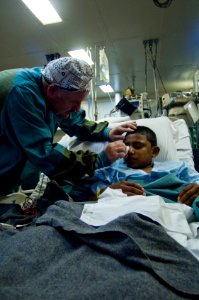 US Navy 080816-N-9620B-007 mdr. Brian Alexander, an optometrist from Portsmouth Naval Hospital, checks on Ches Lacallo after surgery to remove an abnormal growth from his right eye aboard the amphibious assault ship USS Kearsar photo