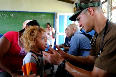 US Navy 080817-N-7955L-021 Lt. Cmdr. Louis Cimorelli, assigned to the amphibious assault ship USS Kearsarge (LHD 3), examines a child at the Betania medical clinic photo