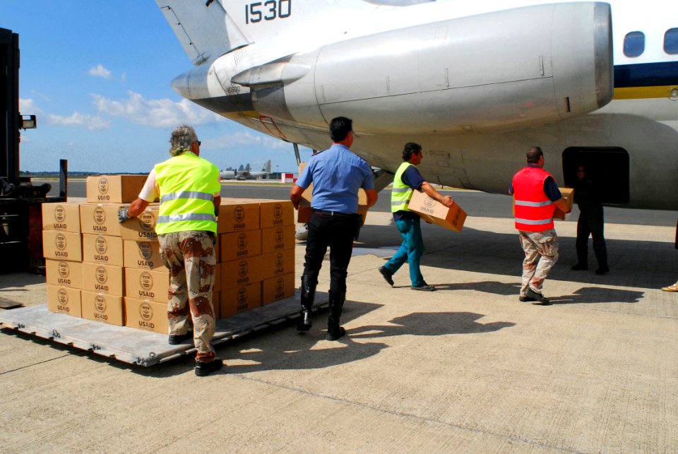 US Navy 080818-N-5821P-003 Italians working for the 405th Army Field Support Battalion and local law enforcement assist Fleet Logistics Support Squadron (VR) 46 crew members in loading humanitarian supplies onto a C-9B Skytrain