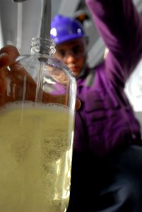 US Navy 080815-N-7730P-049 Aviation Boatswain's Mate (Fuels) 3rd Class Jeremy Curtis fills a sample bottle used for testing fuel purity