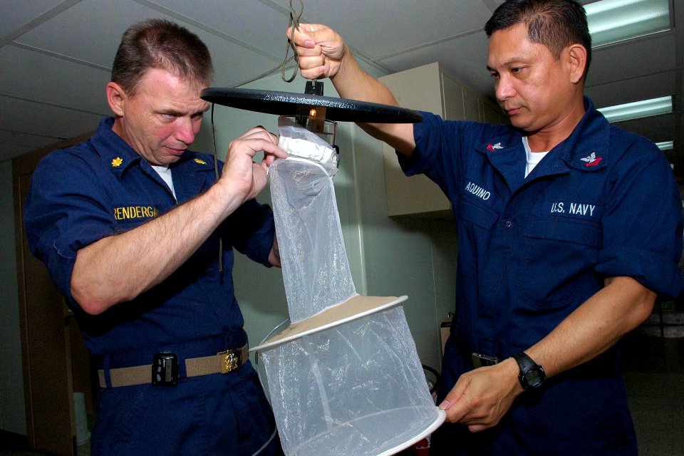 US Navy 080817-N-5086M-002 Lt. Cmdr. Brian Prendergast and Hospital Corpsman 2nd Class Edric Aquino assemble a catch net on a light trap