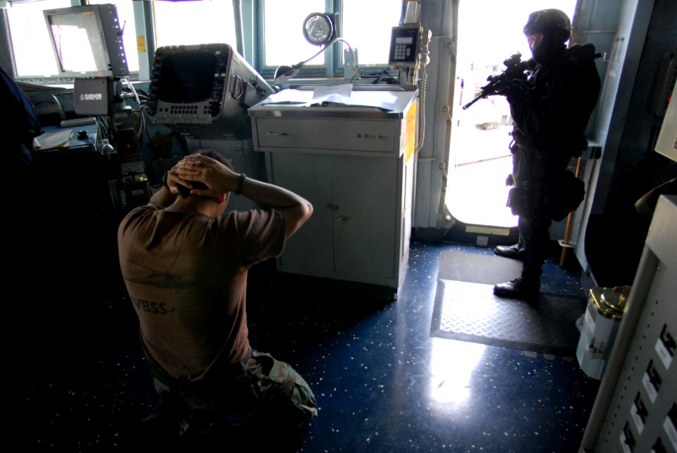 US Navy 080818-N-1635S-013 Operations Specialist 2nd Class Benjamin Ericson kneels with hands behind his head