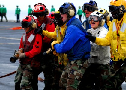 US Navy 080822-N-2638R-004 Air Department Sailors motivate each other while fighting a simulated fire during flight deck drills