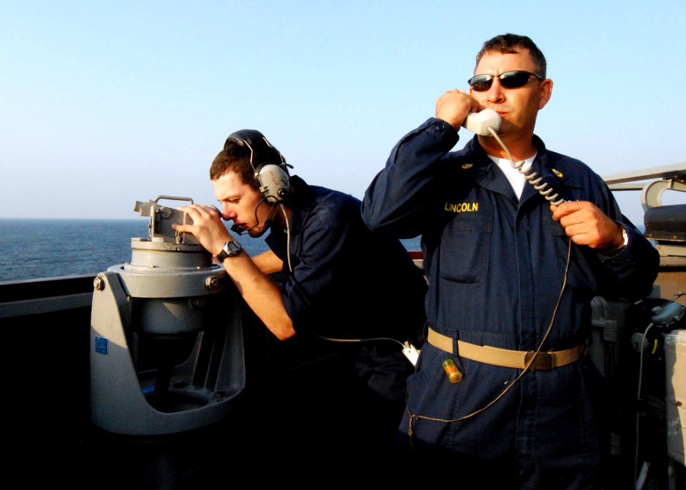 US Navy 080822-N-4044H-006 Chief Electrician's Mate Russell Lincoln informs ship's company of on coming ships while Quartermaster Seaman Apprentice Derek Evoy looks through a telescopic alidade