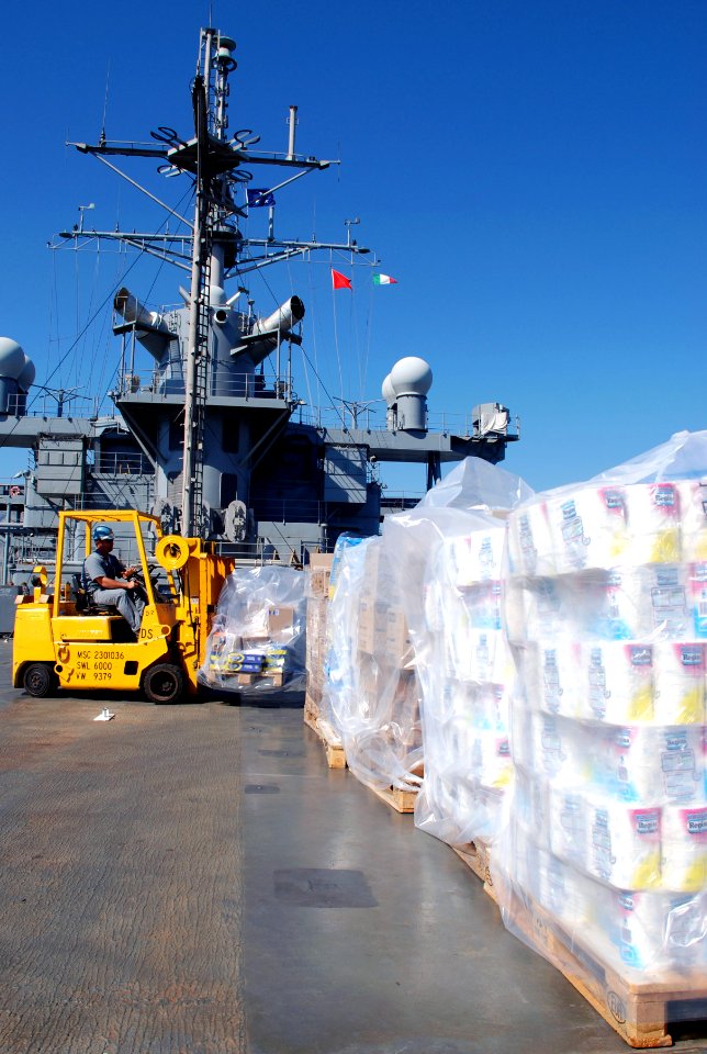 US Navy 080819-N-6544L-001 Able Seaman Frank Santana, a Military Sealift Command civilian, moves pallets of humanitarian relief supplies aboard the amphibious command ship USS Mount Whitney (LCC-JCC 20)
