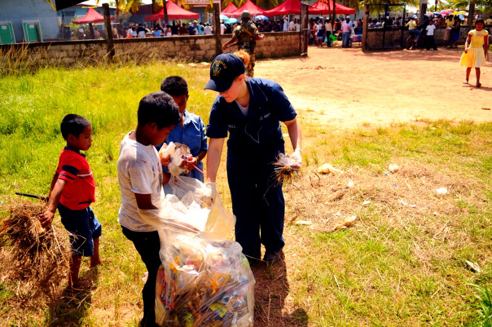 US Navy 080820-N-4515N-327 Local children help Operations Specialist Seaman Stephanie Bell pick up trash
