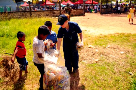 US Navy 080820-N-4515N-327 Local children help Operations Specialist Seaman Stephanie Bell pick up trash