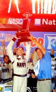 US Navy 080822-N-5345W-225 JR Motorsports driver Brad Keselowski hoists the winner's trophy alongside Food City president and CEO Fred Smith in victory lane
