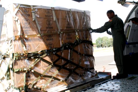 US Navy 080818-N-5821P-023 Aircraft Structural Mechanic 3rd Class Jonathan Mack communicates with the K-loader operator to guide a pallet onto a C-9B Skytrain as the aircraft loads humanitarian supplies