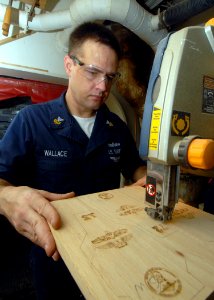 US Navy 080823-N-9079D-092 Machinery Repairman 1st Class Larry W. Wallace, from Bremerton, Wash., cuts out dual warfare plaques with the band saw in the carpentry shop aboard the aircraft carrier USS Abraham Lincoln (CVN 72)