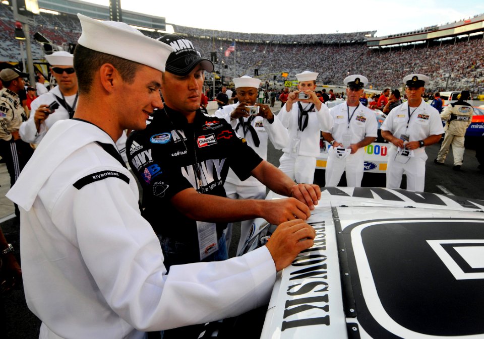 US Navy 080822-N-5345W-104 Fellow Sailors watch as Construction Mechanic 2nd Class David Jellison helps a member of the JR Motorsports team