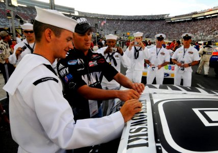 US Navy 080822-N-5345W-104 Fellow Sailors watch as Construction Mechanic 2nd Class David Jellison helps a member of the JR Motorsports team