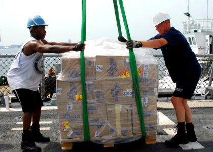 US Navy 080825-N-4044H-062 Boatswain's Mate 3rd Class Anthony Murphy and Chief Electronics Technician David Close prepare a pallet of humanitarian assistance supplies on the weather deck aboard the guided-missile destroyer USS