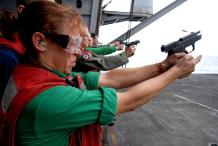 US Navy 080824-N-4005H-367 Aviation Structural Mechanic 3rd Class Erika Mata fires a 9 mm pistol at a target during a small-arms weapons qualifying exercise aboard the Nimitz-class aircraft carrier USS Ronald Reagan (CVN 76) photo