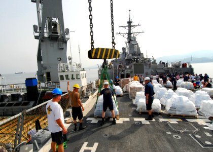 US Navy 080825-N-4044H-011 Lt. j.g. Robert Bailey and Boatswain's Mate Seaman Recruit Eddius Hucks guide a pallet of humanitarian assistance supplies on the weather deck aboard the guided-missile destroyer USS McFaul (DDG 74)