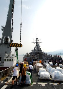 US Navy 080825-N-4044H-009 Sailors aboard the guided-missile destroyer USS McFaul (DDG 74) guide the crane cable onto the ship to transfer pallets of humanitarian assistance from the ship to the crane barge and then to the peop