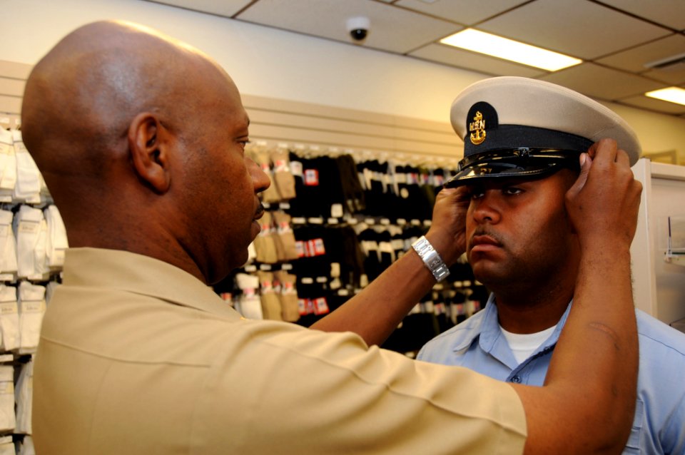 US Navy 080825-N-9758L-026 Chief Information Specialist Technician Dwayne Peterson fits a combination cover on the head of Religious Program Specialist 1st Class Tshombe Harris