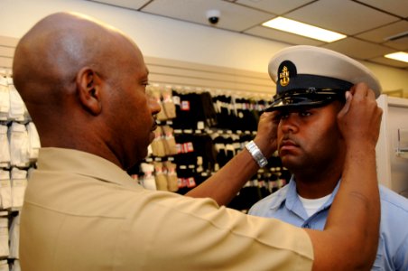 US Navy 080825-N-9758L-026 Chief Information Specialist Technician Dwayne Peterson fits a combination cover on the head of Religious Program Specialist 1st Class Tshombe Harris