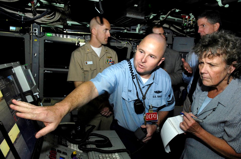 US Navy 080828-N-8467N-002 Electronics Technician 1st Class John Savoie explains the photonics system onboard the fast-attack submarine Pre-Commissioning Unit (PCU) New Hampshire (SSN 778) to Seacoast Media reporter Deborah Mcd