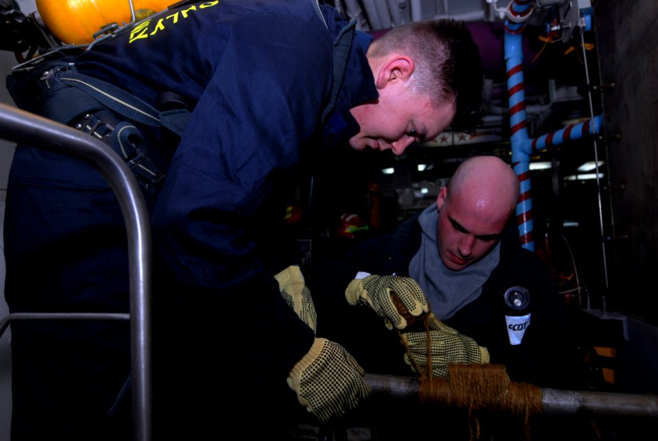 US Navy 080827-N-3610L-114 Machinist's Mate 3rd Class Michael Scholten and Machinist's Mate 3rd Class Kyle Auger-Albanese repair a simulated cracked pipe