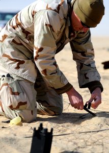 US Navy 111212-N-BA263-460 Lt. j.g. Jacob Mello, assigned to Commander, Task Group (CTG) 56.1, attaches electric blasting caps to a demolition char