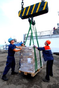 US Navy 080827-N-4044H-108 U.S. Coast Guard Seaman Tyler Lewis and U.S. Coast Guard Seaman Keri Myers assist a Georgian pier worker as a pallet of humanitarian assistance supplies is transported off the U.S. Coast Guard Cutter