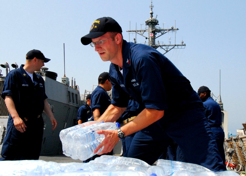 US Navy 080824-N-4044H-095 Cryptologic Technician 1st Class Jed Morris stacks bottles of water aboard the guided-missile destroyer USS McFaul (DDG 74), which will be included in the humanitarian supplies for the people of Georg