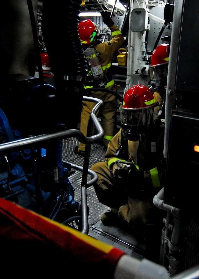 US Navy 080827-N-0807W-368 A hose team enters auxiliary room number one during a main space fire drill.
