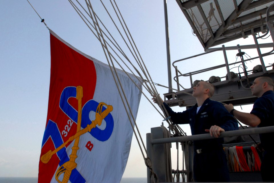 US Navy 080830-N-3610L-225 Quartermaster 3rd Class Nicolas Rader and Quartermaster 3rd Class Lawrence Orso hoist the battle flag of the Nimitz-class aircraft carrier USS Ronald Reagan (CVN 76)