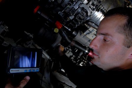 US Navy 080831-N-7730P-082 Aviation Machinist's Mate 2nd Class Cameron Prince uses a borescope to inspect foreign object damage to the engine of an F-A-18E Super Hornet