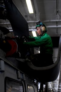 US Navy 080829-N-3610L-162 Aviation Machinist's Mate 1st Class Joselito Camiling perches himself on a HH-60H Sea Hawk to perform routine maintenance in hangar bay 1 aboard USS Ronald Reagan (CVN 76)